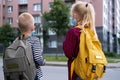 Back view Brother and sister going school after pandemic over. Kids wearing mask and backpacks protect and safety from Royalty Free Stock Photo