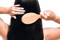 View of brunette beautiful woman brushing long straight healthy and shiny hair with comb isolated on white Royalty Free Stock Photo