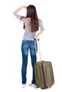 Back view of brunette woman with suitcase looking up