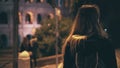 Back view of brunette woman walking late at night in Rome, Italy. Girl cross the road at crosswalk near the Colosseum. Royalty Free Stock Photo