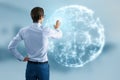 Back view of businessman hand using glowing blue polygonal globe on blurry office interior background. Global technology and Royalty Free Stock Photo
