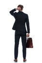Back view of businessman holding his briefcase and scratching head Royalty Free Stock Photo