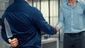 Back view of businessman shaking hands with a knife behind his back. Royalty Free Stock Photo