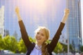 Back view of businesswoman facing the modern office building with arms raised as winner. Happy business lady celebrating Royalty Free Stock Photo