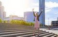 Back view of businesswoman facing the modern office building with arms raised as winner. Happy business lady celebrating success Royalty Free Stock Photo