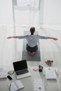 Back view of businesswoman practicing yoga in lotus position on mat in office