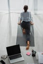 View of businesswoman practicing yoga and stretching legs on mat in office