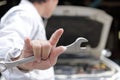 Back view of car mechanic man holding wrench and his hand with i love you sign with car in open hood at the repair garage backgrou Royalty Free Stock Photo