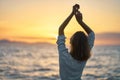 Back view carefree woman with hands up to the sky looking at sunset over the sea. Royalty Free Stock Photo