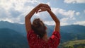 Back view carefree woman holding hands over head relaxing on mountains close up.