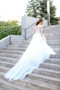 Back view of caucasian bride walking on concrete stairs and wearing white dress. Royalty Free Stock Photo