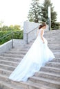 Back view of caucasian fiancee walking on concrete stairs and wearing white dress. Royalty Free Stock Photo