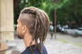 Back view of a caucasian man with dreadlocks and sidecut on a summer street