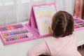 Back view of child girl draws with colored pencils or felt tipped pens, making illustration, sitting at desk in her room, having Royalty Free Stock Photo