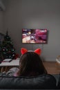 Back view of a child girl sitting on the couch and playing video game or watching cartoons on tv. Wireless funny pink Royalty Free Stock Photo