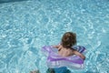 Back view of a child with a lifebuoy swimming in the pool