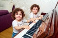 Two funny twin playing the piano together, smiling, laughing. Children learn to play the piano. The concept of training children. Royalty Free Stock Photo