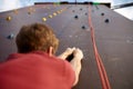 Back view close-up of climber hands on a rock hook of the artificial climbing wall outdoors. Young healthy sporty Royalty Free Stock Photo