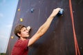 Back view close-up of climber hands on a rock hook of the artificial climbing wall outdoors. Young healthy sporty Royalty Free Stock Photo