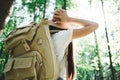 Back view of close-up traveler backpack and hipster girl wearing hat. Young brave woman traveling alone among trees in forest on o