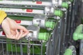 Back view closeup with a selective focus of a girl taking a shopping cart from a stand outside a supermarket Royalty Free Stock Photo