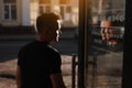 back view of confident young man opening the glass door while walking out on street from the modern building, coffee Royalty Free Stock Photo