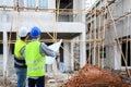 Back view of Construction engineer and architect check plan working with the blueprint on construction site. They are in safety Royalty Free Stock Photo