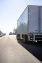 Back view of convoy of big rigs semi trucks running with semi trailers on the divided road