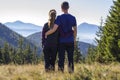 Back view of couple athletic boy and blond girl standing together embraced enjoying breathtaking view of magnificent Carpathian m Royalty Free Stock Photo