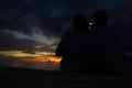 Back view of couple doing photo on the beach with a beautiful sunset in background