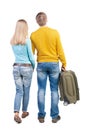 Back view of couple with green suitcase looking up.