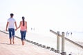 Back view, couple holding hands and walk on beach, romantic date and commitment with trust. Love, care and people Royalty Free Stock Photo