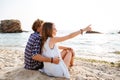 Back view of couple sitting and pointing away on beach Royalty Free Stock Photo