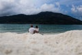 Back view couple sitting on the sandy beach