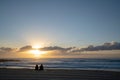 Back view of a couple sitting on the sandy beach watching the sea during cloudy sunset Royalty Free Stock Photo