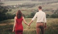 Back view couple walking away in the field, view of couple holding hands Royalty Free Stock Photo