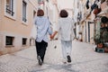 Back view of tourist couple hugging and walking on Lisbon street, enjoying sightseeing outdoors Royalty Free Stock Photo