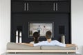 Back view of couple watching movie on television in living room
