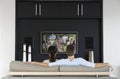 Back view of couple watching movie on television in living room