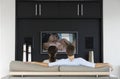 Back view of couple watching romantic movie on television in living room