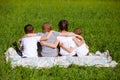 Back view of cute kids seated on green grass