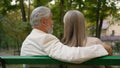 Back view cute positive 70s elderly couple retired happy family relaxing outdoors city nature park bench. Married spouse Royalty Free Stock Photo