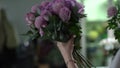 Back view of cute young woman florist wearing apron compose new bouquet.