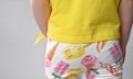 back view of a detail of children& x27;s summer wardrobe - a yellow cotton T-shirt with a short sleeve and colorful legends