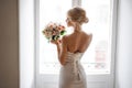 Back view of the elegant blonde bride dressed in a white dress holding a wedding bouquet Royalty Free Stock Photo