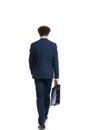 Back view of elegant businessman walking and holding suitcase Royalty Free Stock Photo