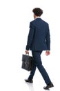 Back view of elegant young businessman holding suitcase and walking Royalty Free Stock Photo