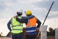 Back view of Engineer and foreman worker checking project at building site, Engineer and builders in hardhats in infrastructure Royalty Free Stock Photo