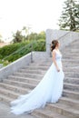 Back view of european bride walking on concrete stairs and wearing white dress. Royalty Free Stock Photo