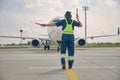 Man signaling the pilot with marshalling wands